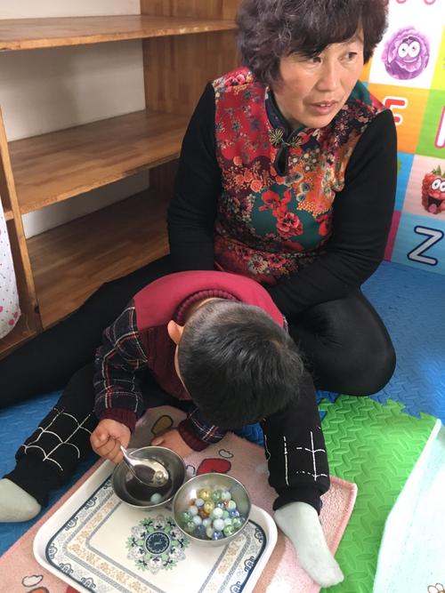 家长陪宝宝玩舀米游戏锻炼手眼协调