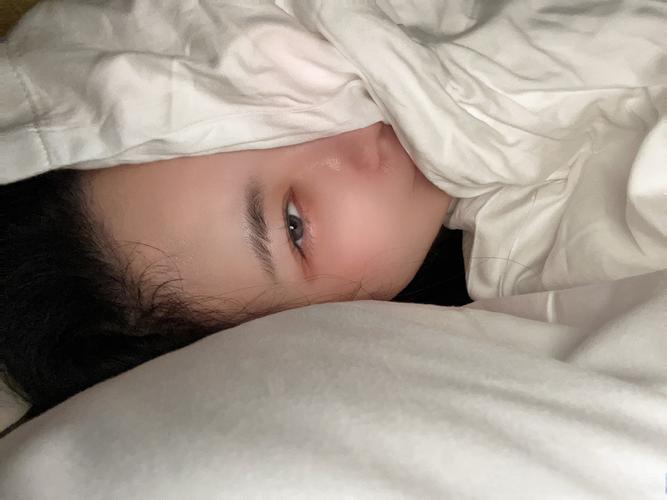 夜晚一个男孩在床上蒙着被子偷偷哭泣