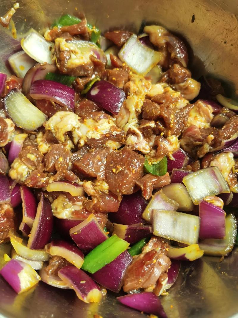 玻璃碗中羊肉块加洋葱丝和酱料腌制