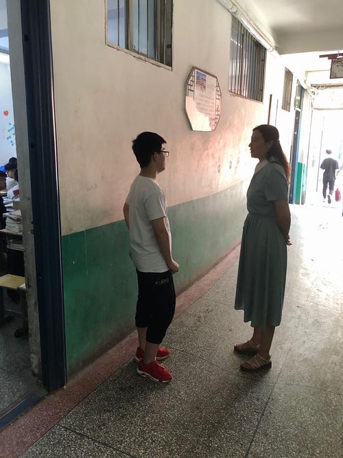 中学校长蹲在走廊台阶和刚下课的年轻教师谈心的现场