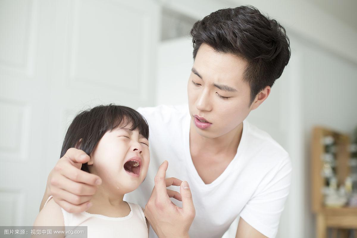 爸爸蹲下来轻抚哭泣小女孩肩膀
