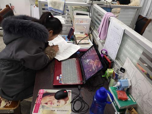 乡村小学办公室教师伏案改作业疲惫背影图