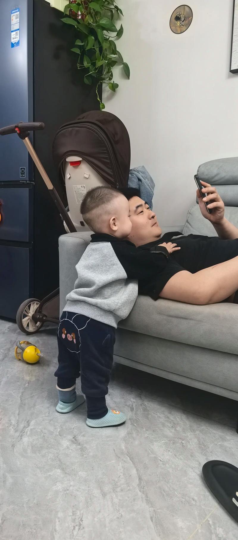 爸爸和孩子坐在草地上看手机僵硬的亲子关系对比图