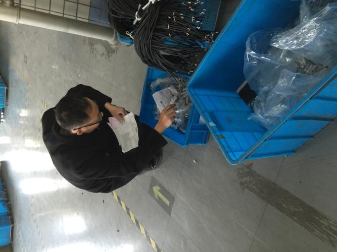 机械车间工人手持皱巴巴领料单对照货架找物料