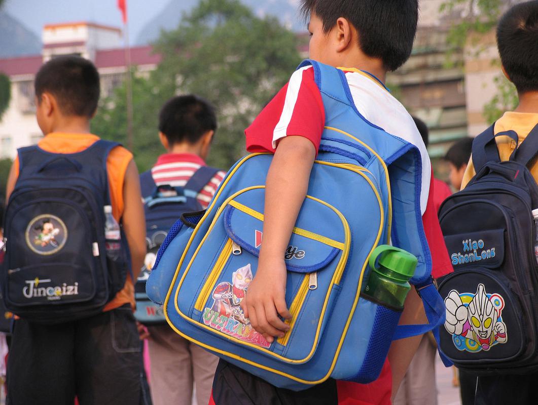 小学生校门口攥书包带低头场景