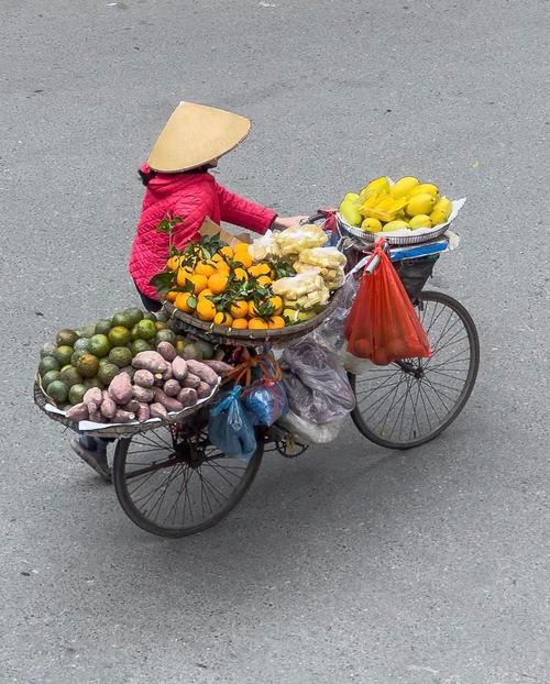街头摄影师微笑着与摊贩互动,相机挂在胸前,氛围轻松