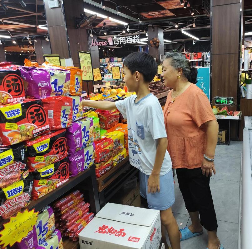 奶奶带着小孙子在菜市场指认沾着水珠的上海青
