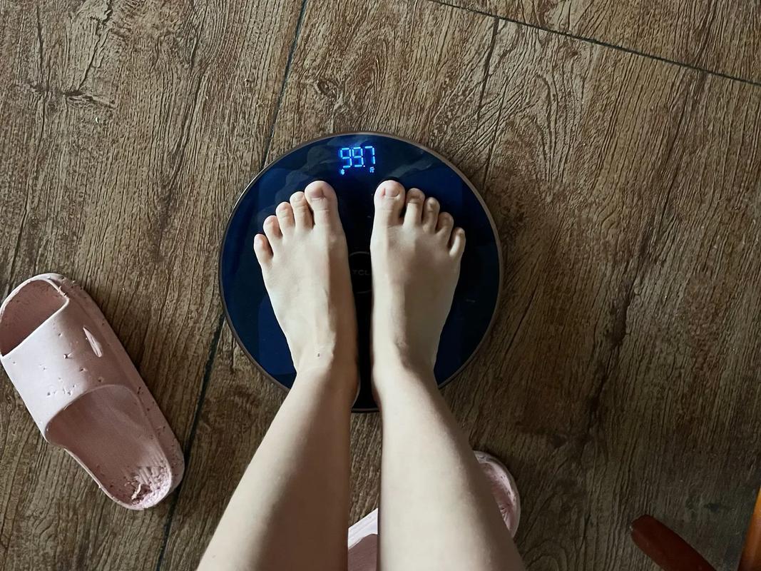 居家场景里普通人穿棉拖鞋站在电子体重秤上低头看读数的日常