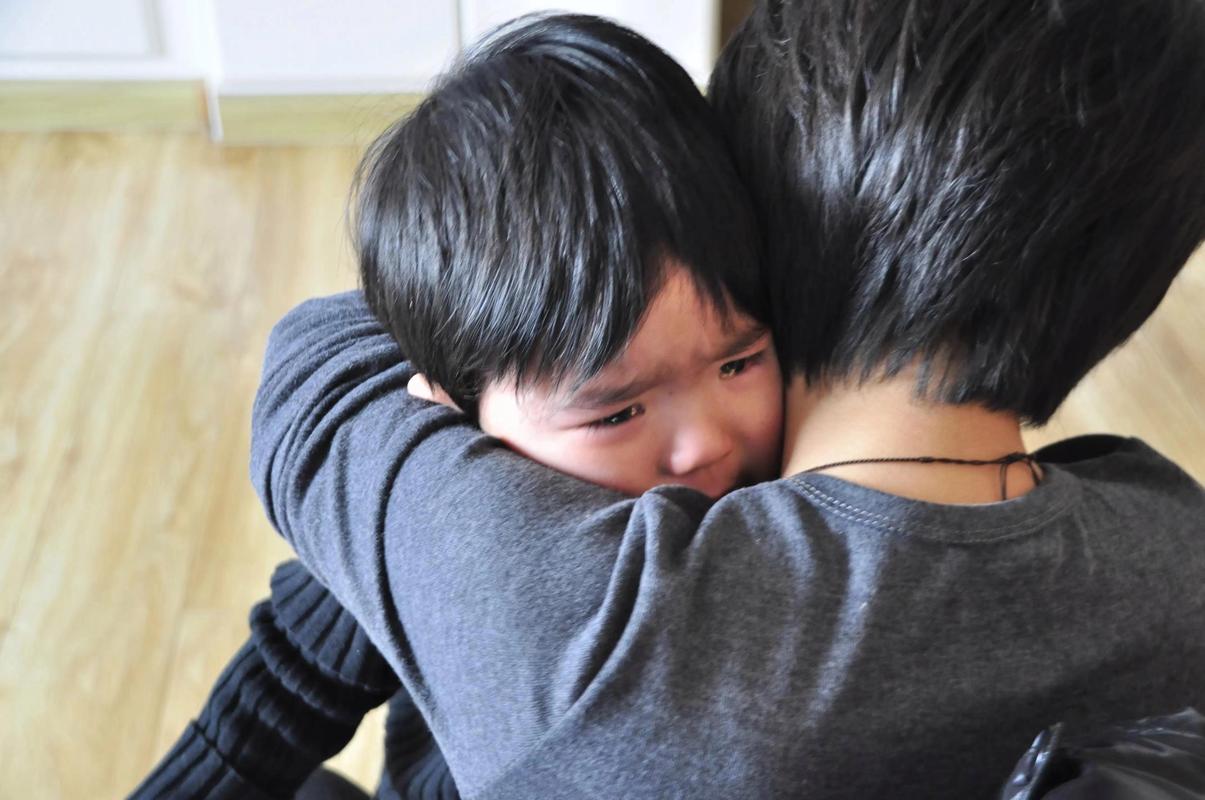 妈妈抱着哭泣的孩子轻声安慰的场景特写