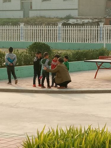 小学课间校长蹲花坛和学生聊天实景