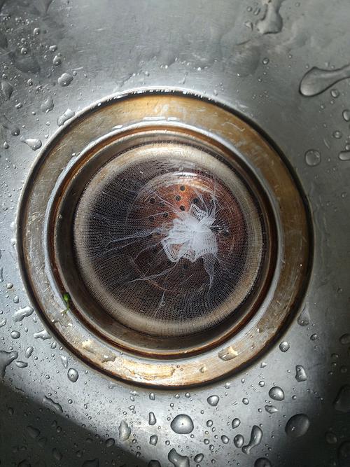 厨房水槽里泡着小苏打和白醋的抽油烟机金属滤网