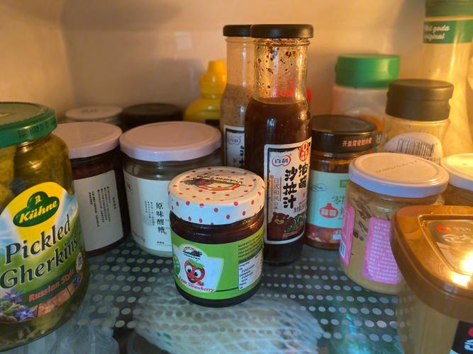 冰箱冷藏层整齐摆放的开封蚝油、沙拉酱、黄豆酱玻璃储物罐