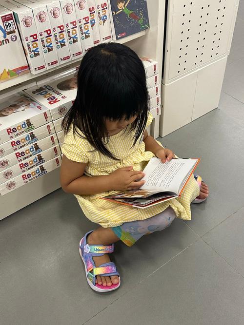 书店儿童阅读区蹲在角落看书的小女孩