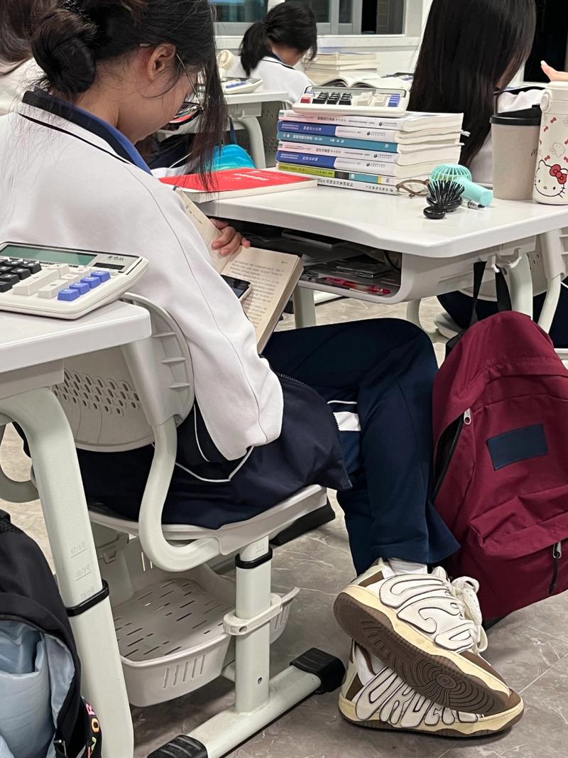 晚自修教室学生偷偷把练习册盖在手机上的场景