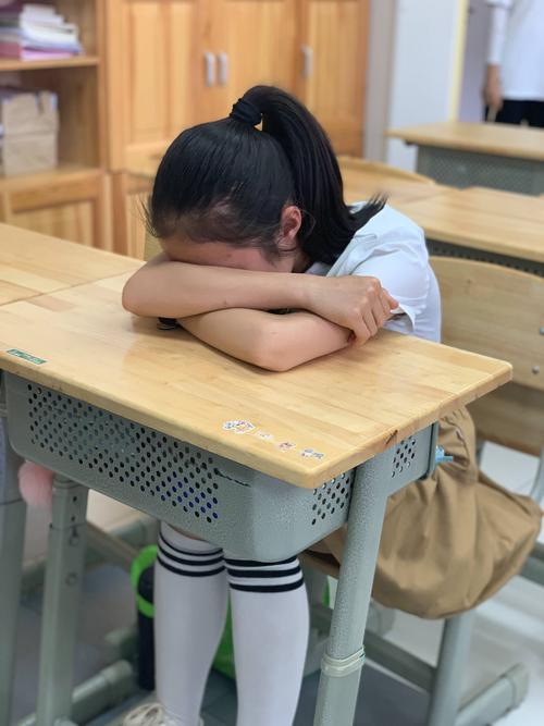 小学课堂上被空泛表扬后局促攥紧衣角的女学生特写