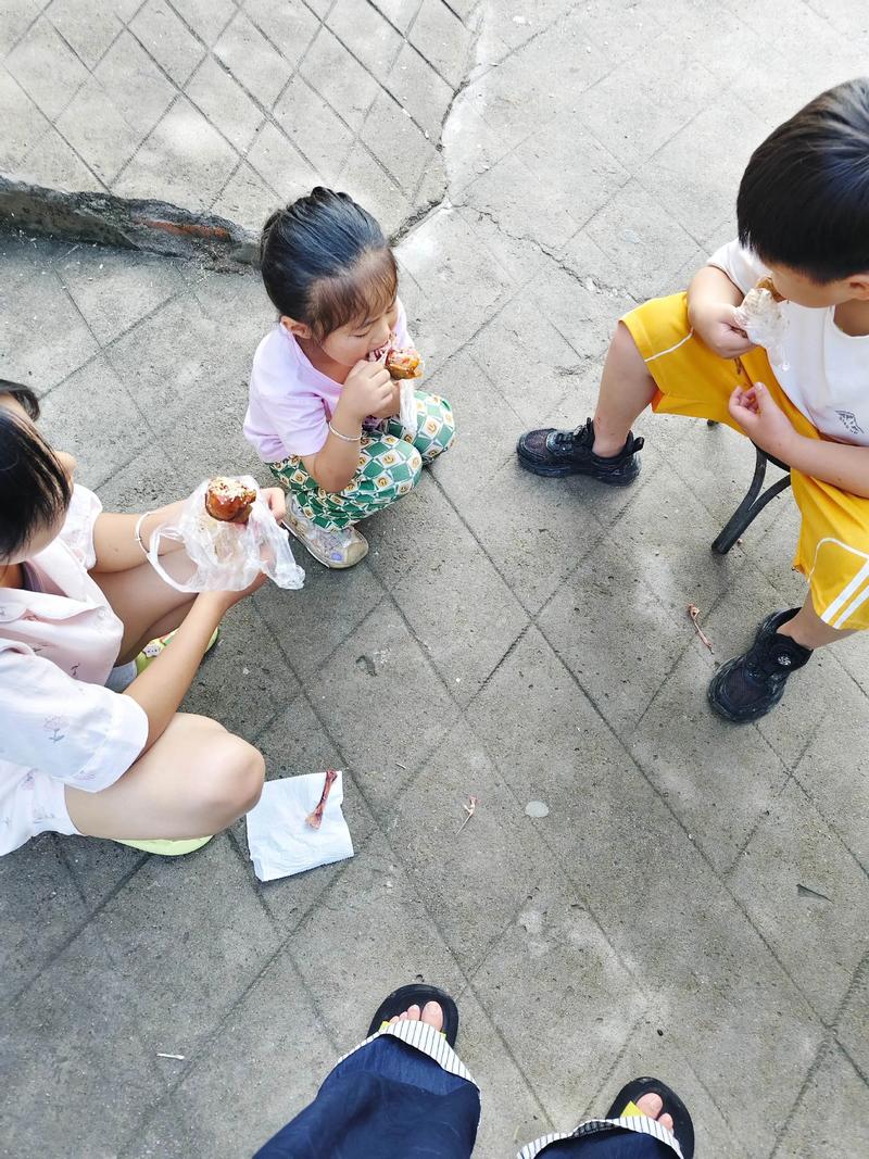妈妈和3岁娃坐在小区台阶上分吃牛奶磨牙饼干的实拍图