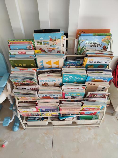 幼儿把绘本歪歪扭扭摆到矮书架上的真实抓拍