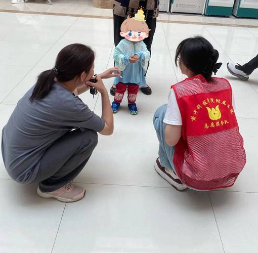 妇幼保健院导诊台小志愿者给小朋友递贴纸的实拍