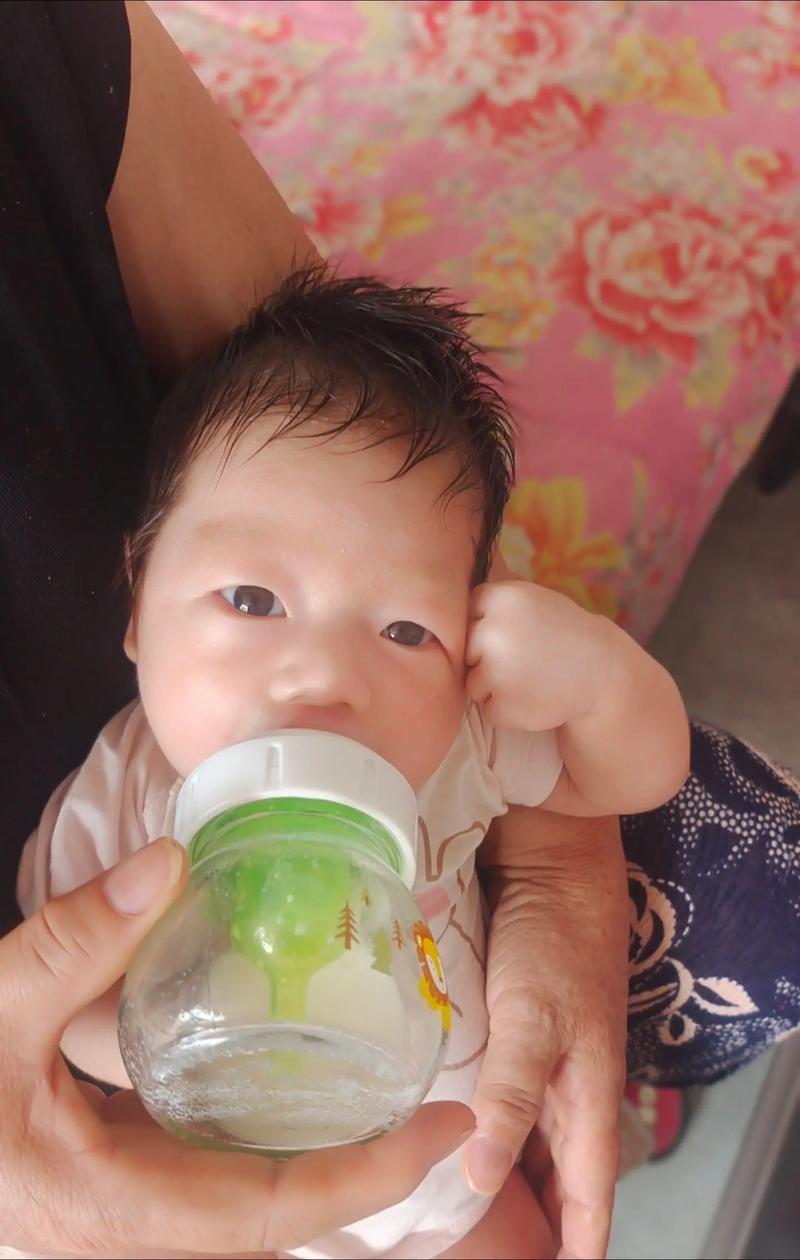 婴儿满足地依偎在母亲胸前喝奶的特写镜头