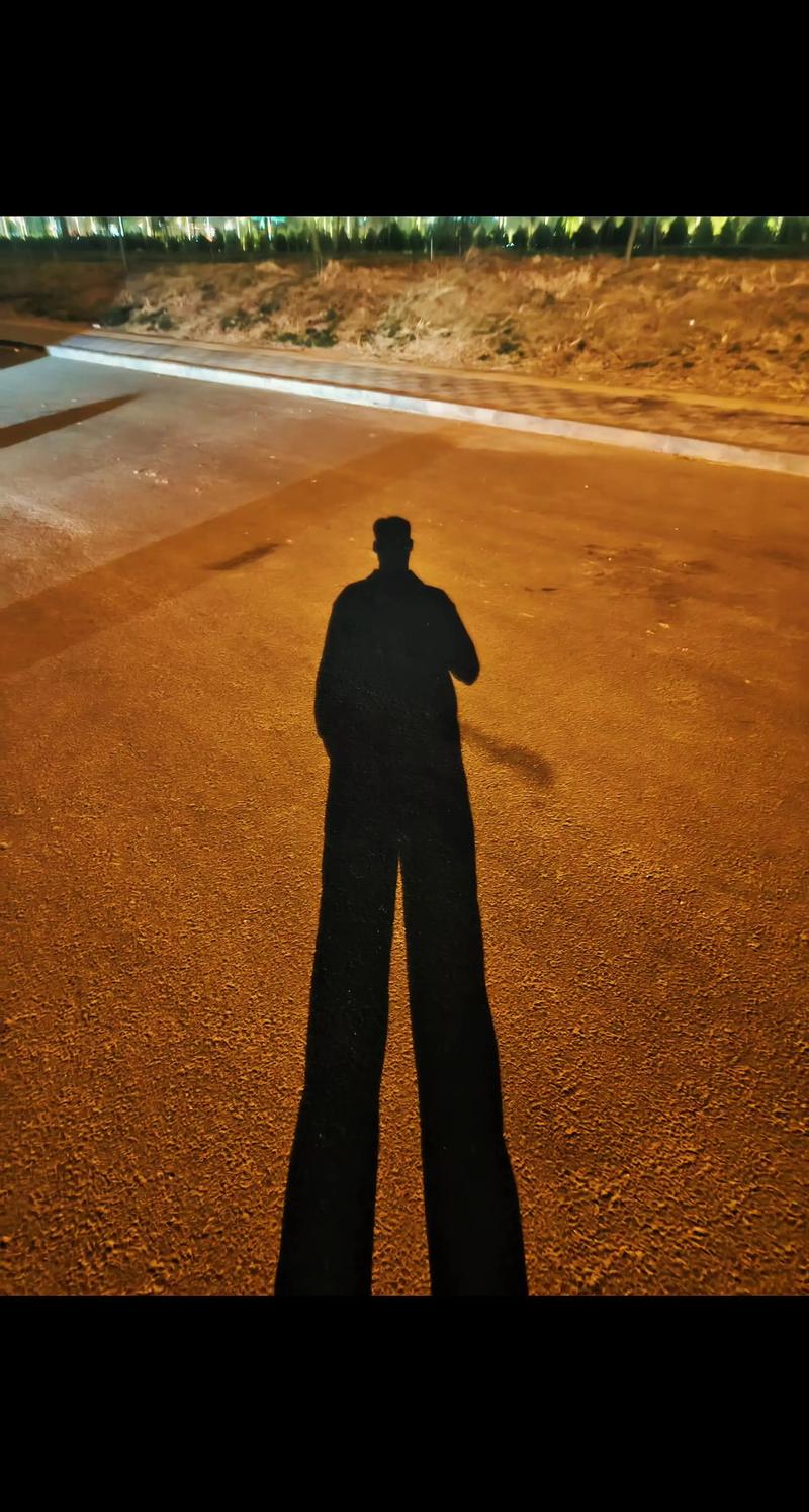 夜间路灯下人物的拖长影子剪影