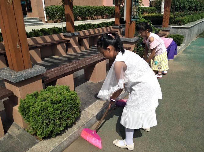 学生穿统一围裙举塑料铲子在操场摆拍劳动活动