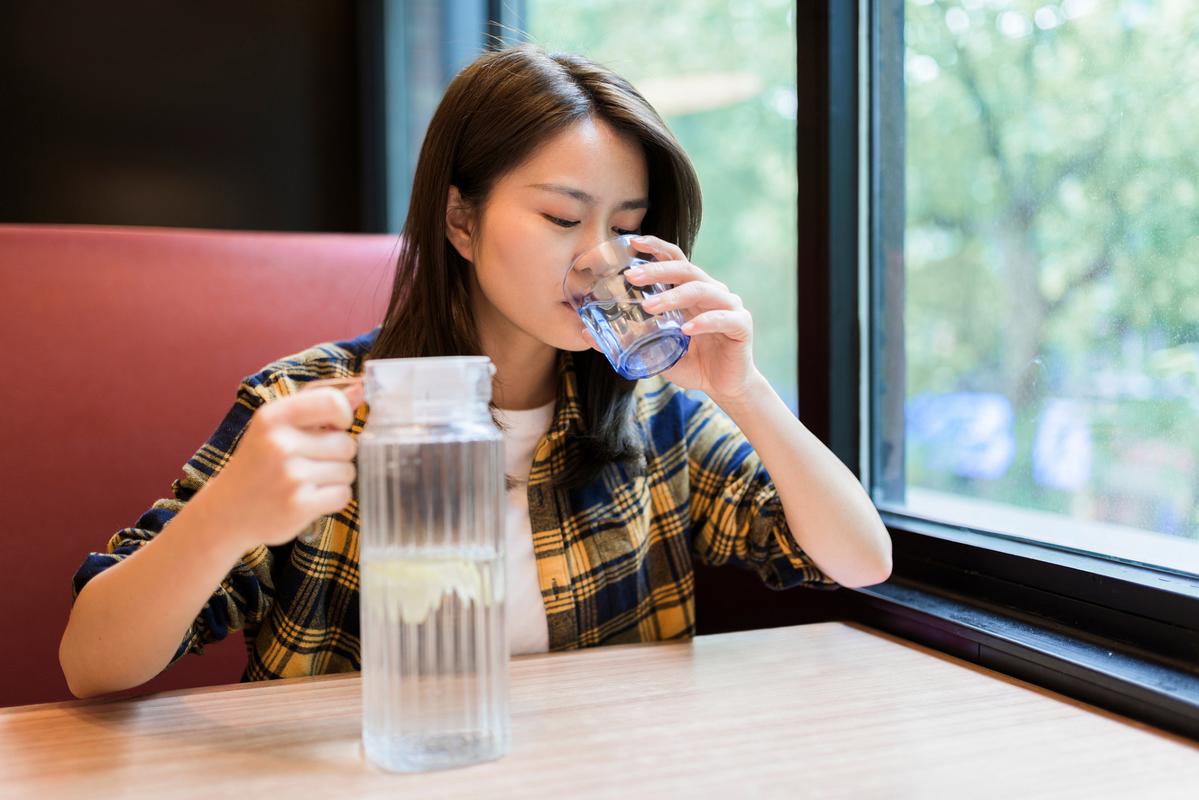 上班族站在饮水机旁接热水视线落在杯口的松弛瞬间