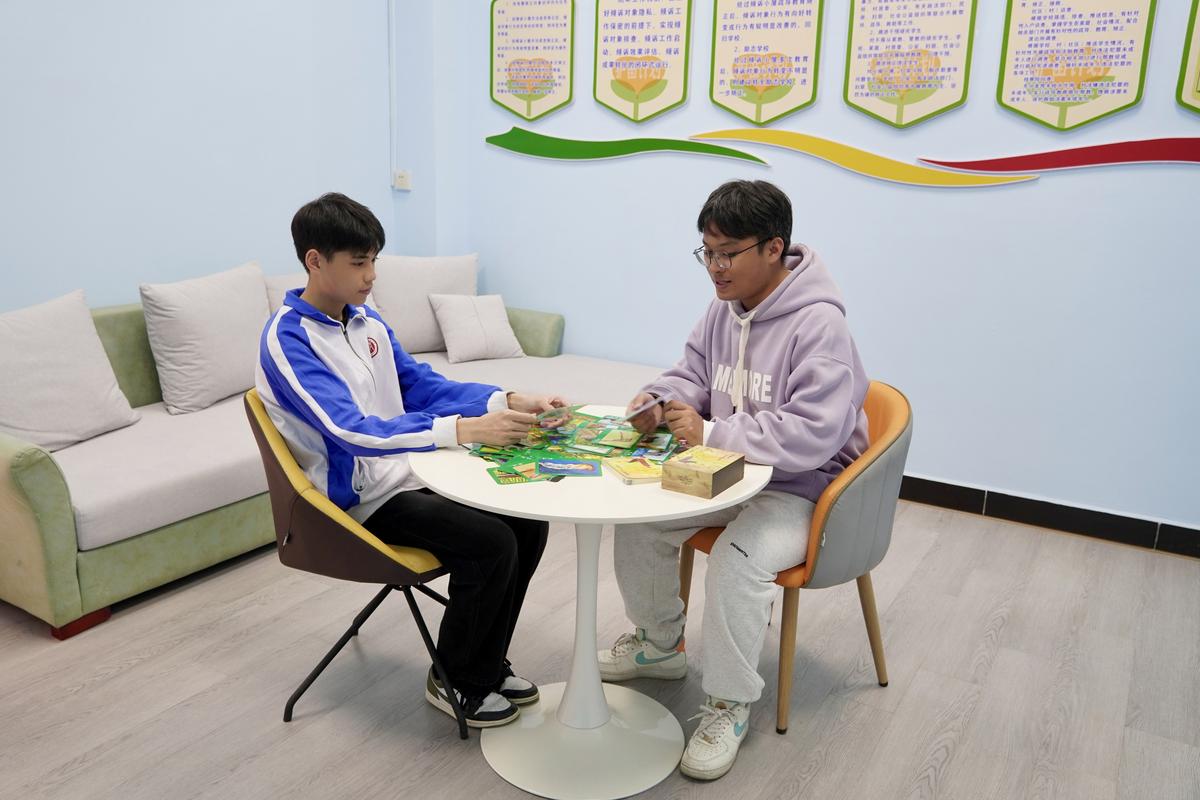 中学心理咨询室里老师和穿校服的女生隔桌轻声对话的实拍