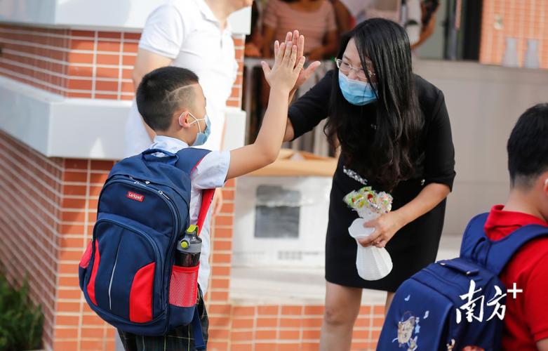 小学老师在校门口微笑着与学生打招呼