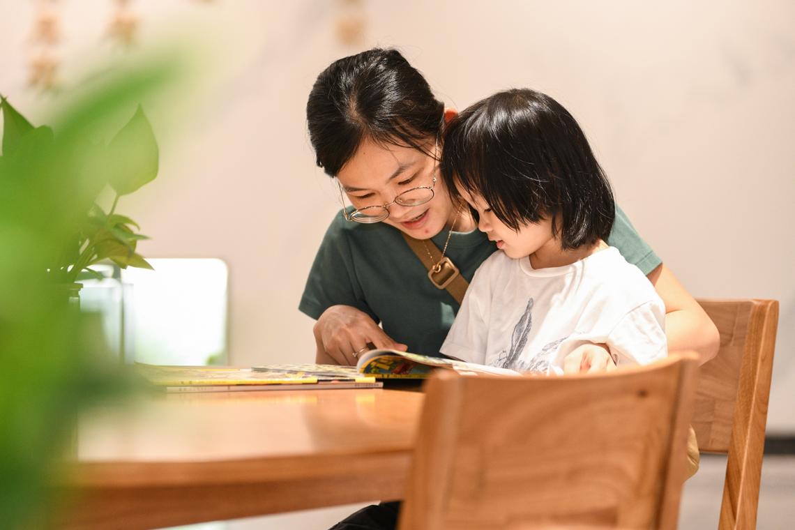 家长和孩子在客厅共读的温馨抓拍