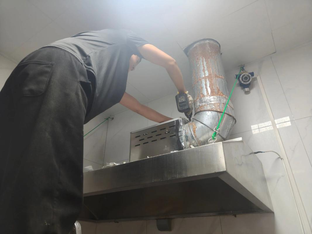保洁人员使用专业蒸汽机清洁厨房油烟机内部