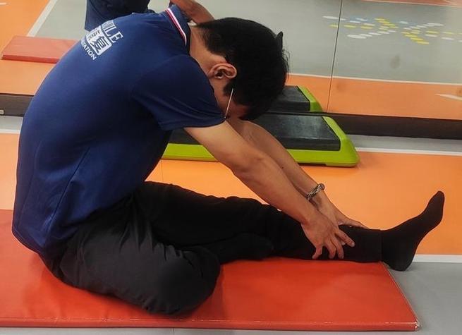 居家客厅坐沙发边缘做腘绳肌拉伸的人