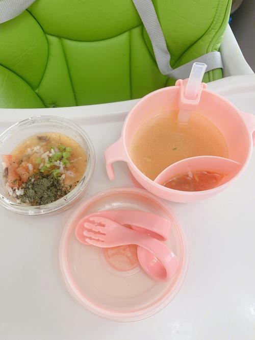 宝宝餐椅上摆放的拆封奶片与清煮青菜的对比实拍