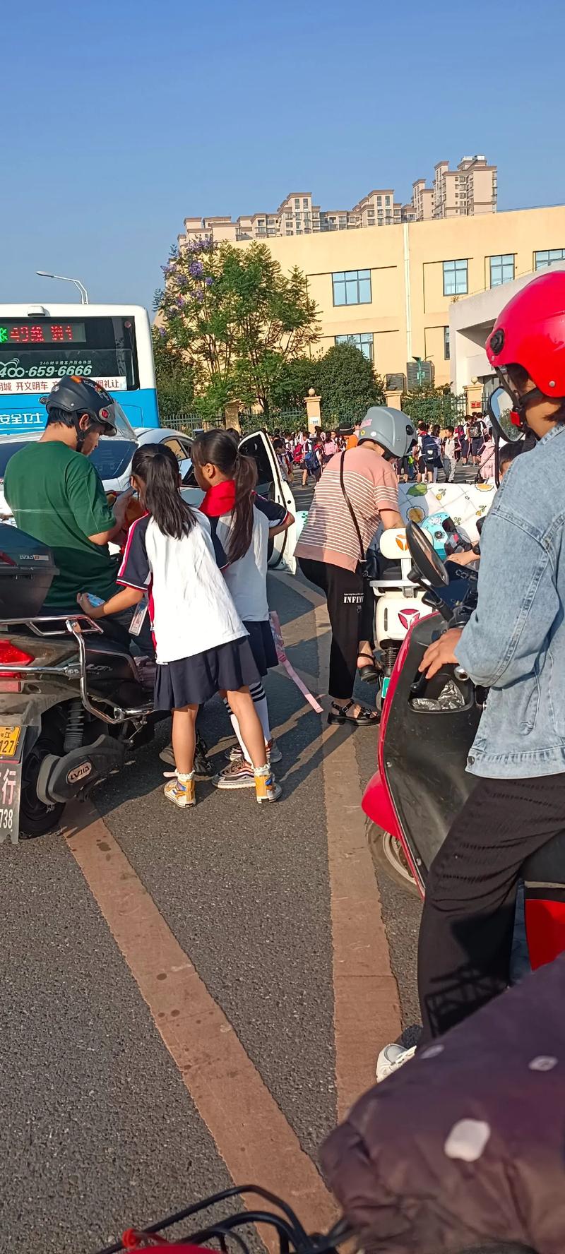 家长骑电动车送孩子上学路上聊天场景