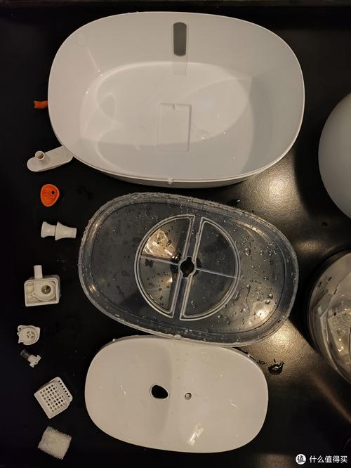 拆解开的哑光陶瓷猫饮水机所有零件整齐摆放在原木桌面的实拍图