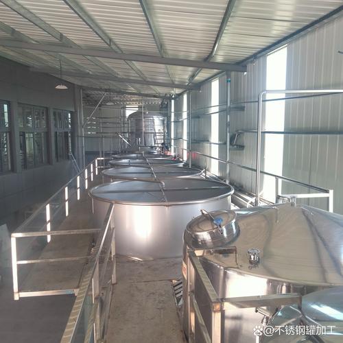 新建的工业发酵罐车间现场，工人正在吊装大型不锈钢罐体