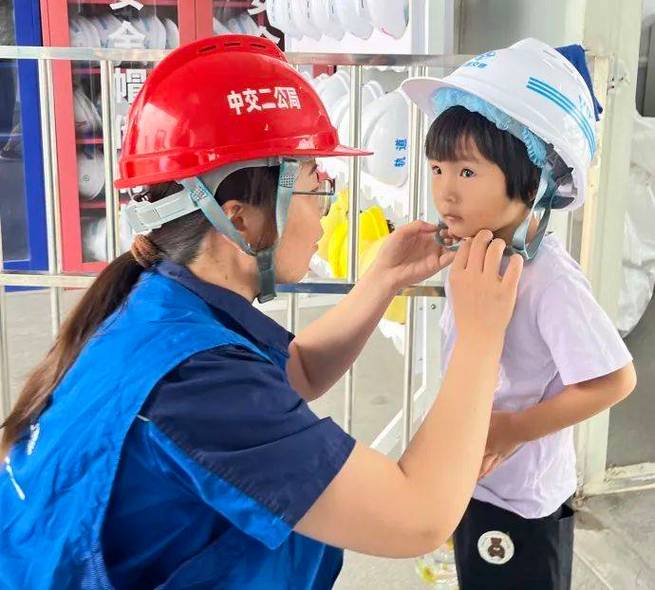 家长与孩子戴着安全帽在工厂通道观察流水线
