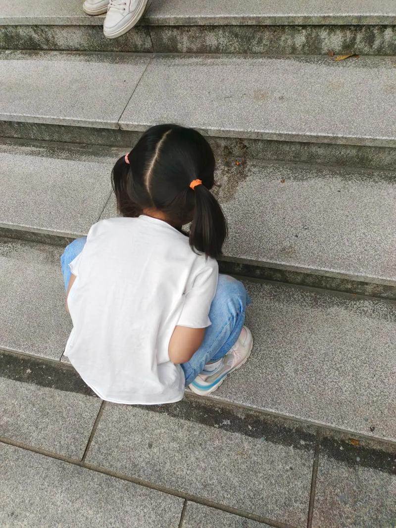 孩子蹲在阳台地面观察蚂蚁搬运食物特写照片