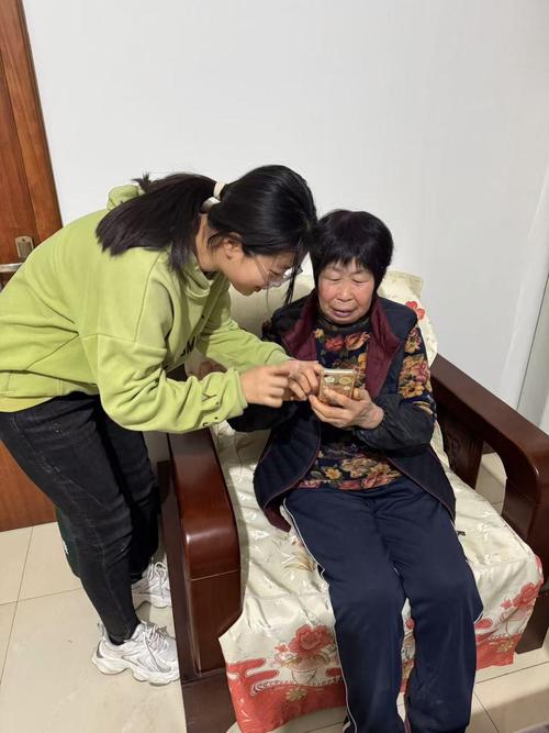 社区助老室内活动老人给小学生看手机里的家庭照片