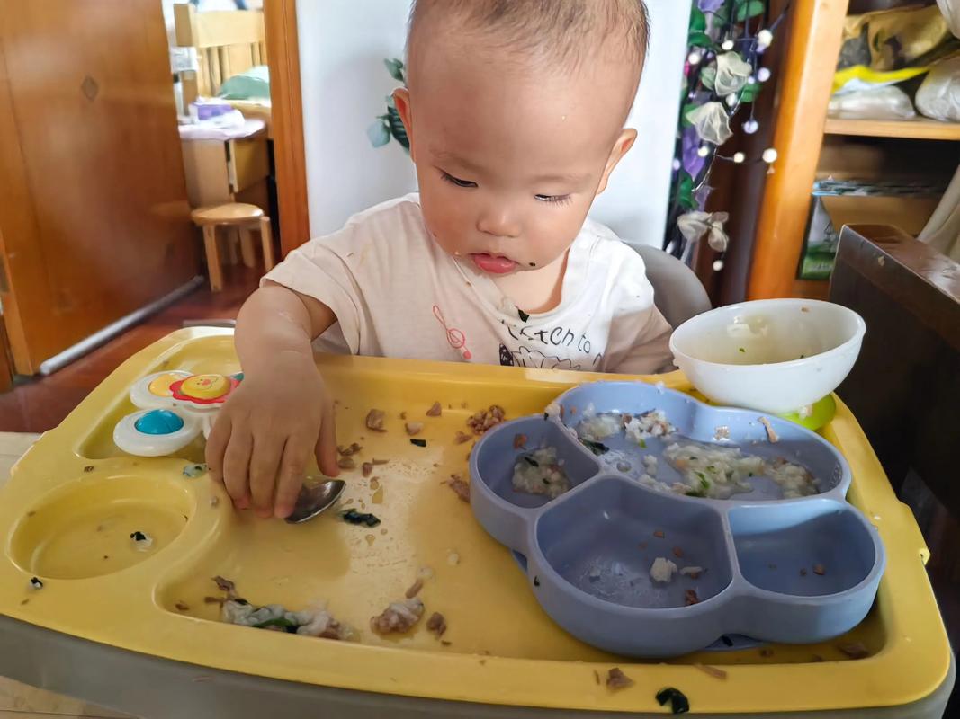 一岁幼儿自己拿勺子吃饭场景