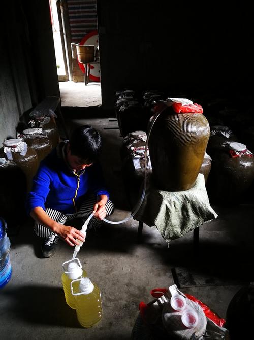 绍兴老酒作坊门口居民拎着塑料桶打黄酒的场景