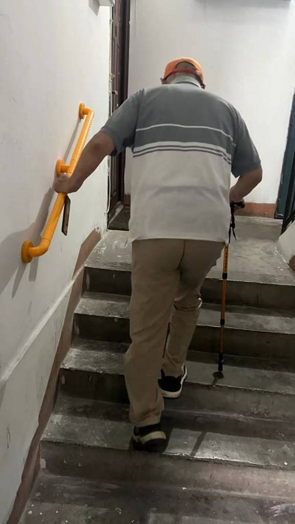 普通居民楼台阶上老人扶着扶手慢走的日常场景