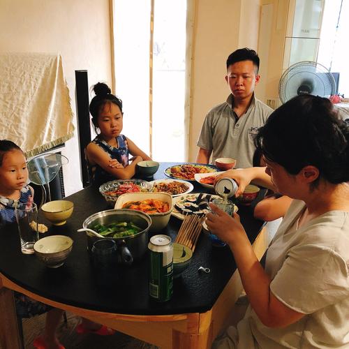 晚饭桌边妈妈笑着听孩子讲学校日常的居家场景