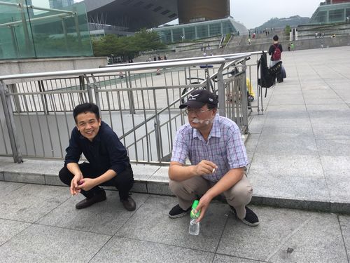 小区楼下男子蹲路边抽烟实景