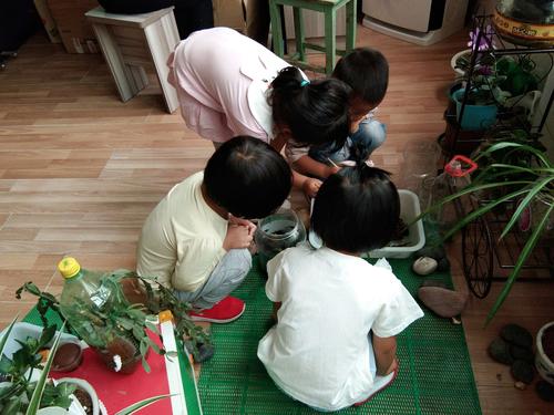 客厅里宝宝蹲看蚂蚁妈妈坐旁喝茶的亲子慢生活场景