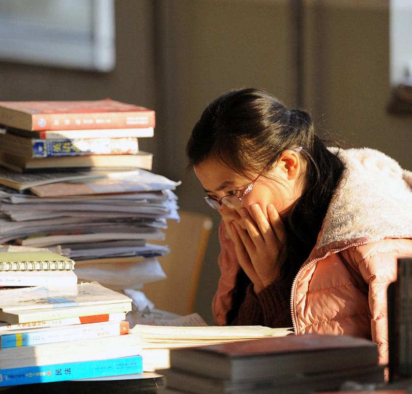 考研学生抱头坐在堆满书籍的桌前