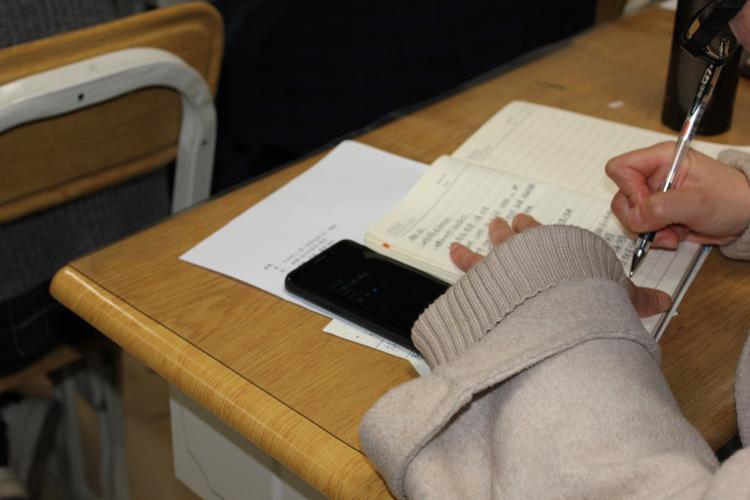 中学教室内家长坐在后排攥着皱成绩单的手部特写