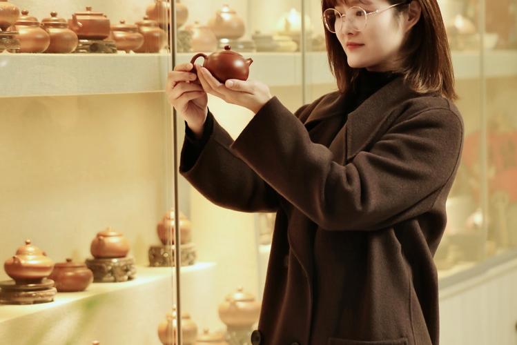 中年女性茶艺师手持紫砂壶从容注水的特写