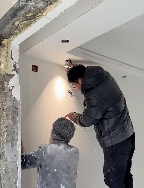 油漆工在灯光下检查墙面打磨平整度