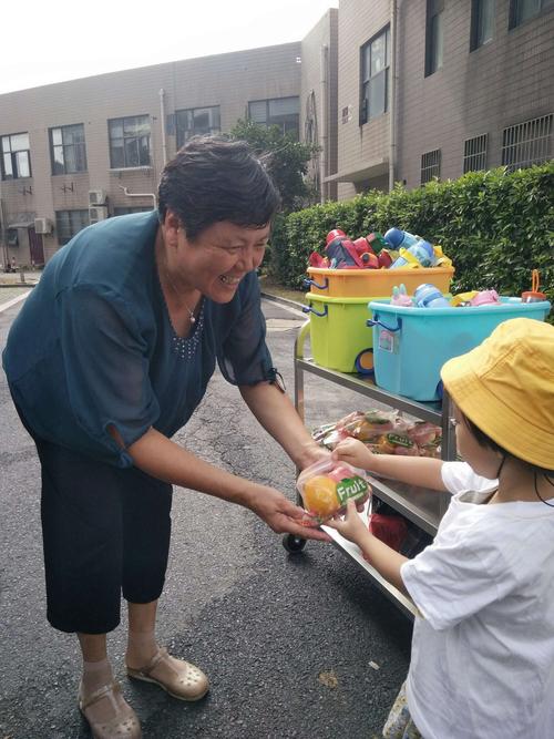 托育园铁栅栏外家长攥着水果袋悄悄目送的实拍