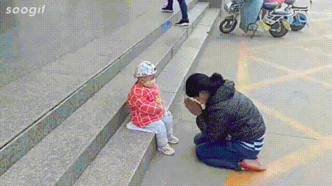妈妈蹲在路边安慰摔车哭泣的小孩
